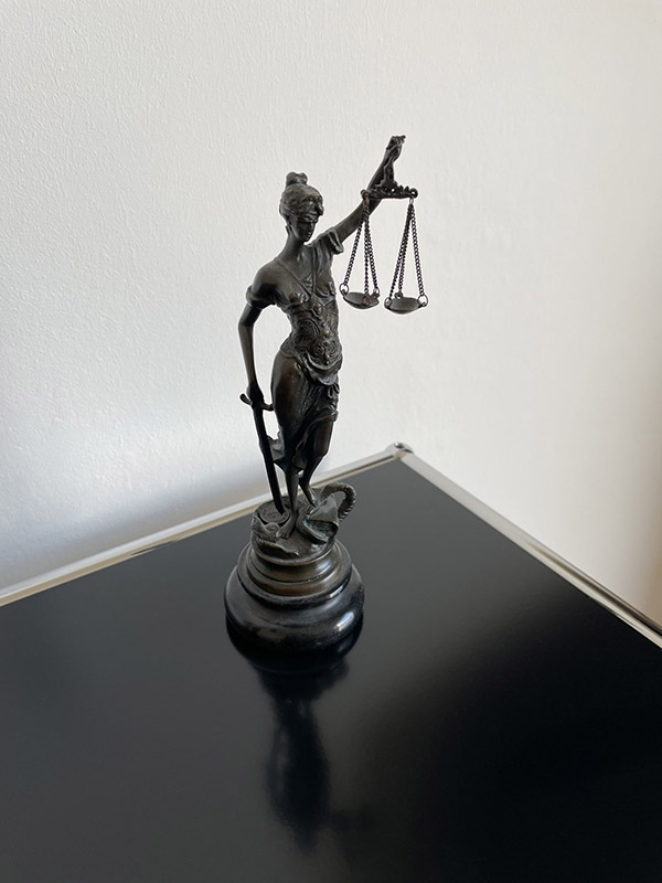 Die Figur der Justitia auf einem schwarzem Glastisch.